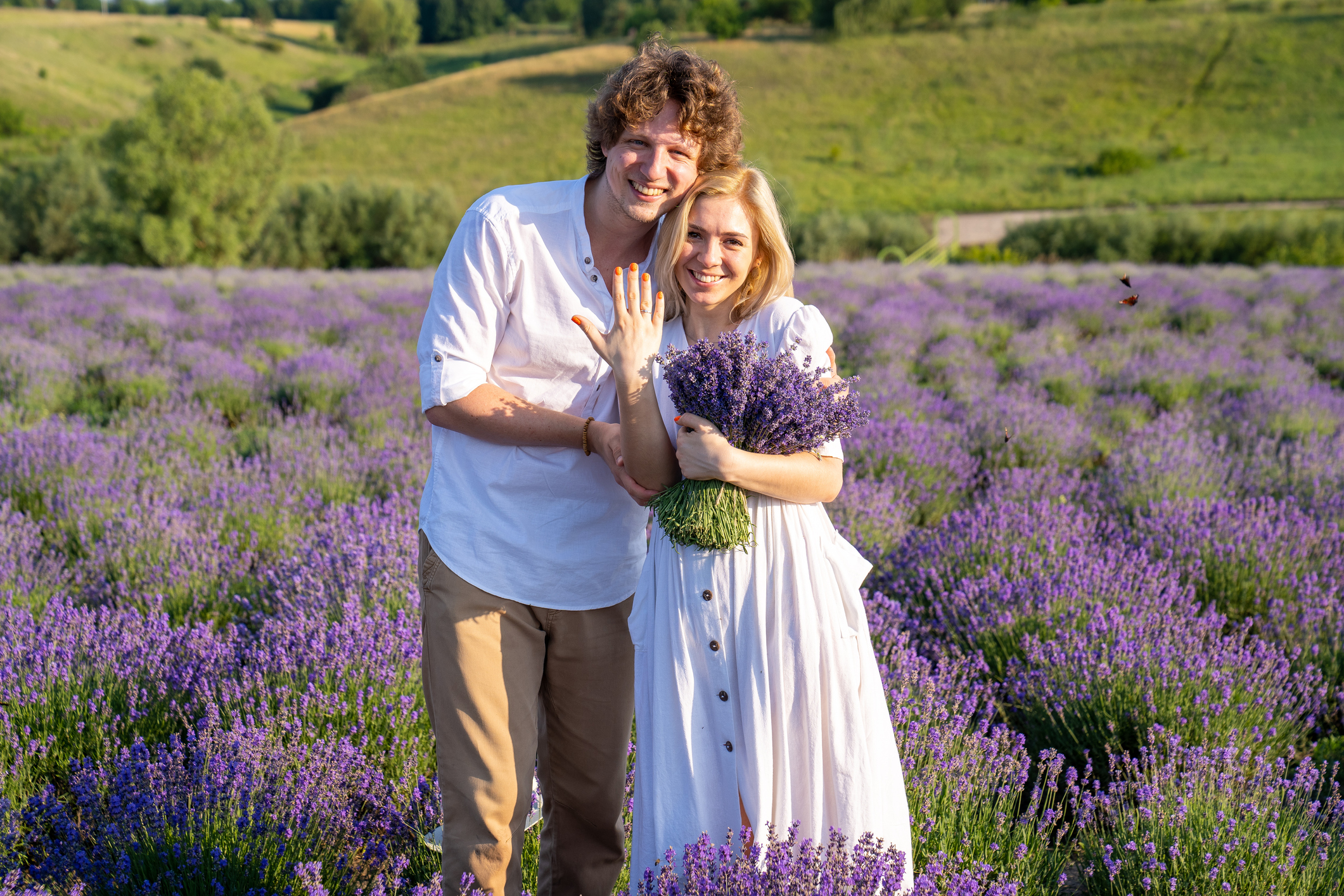 couple in white matching outfit in lavender field, photo session. man is proposing to woman with ring. engagement day. romance and true love in relationship. They are happy hugging and kissing. Engaged to get married