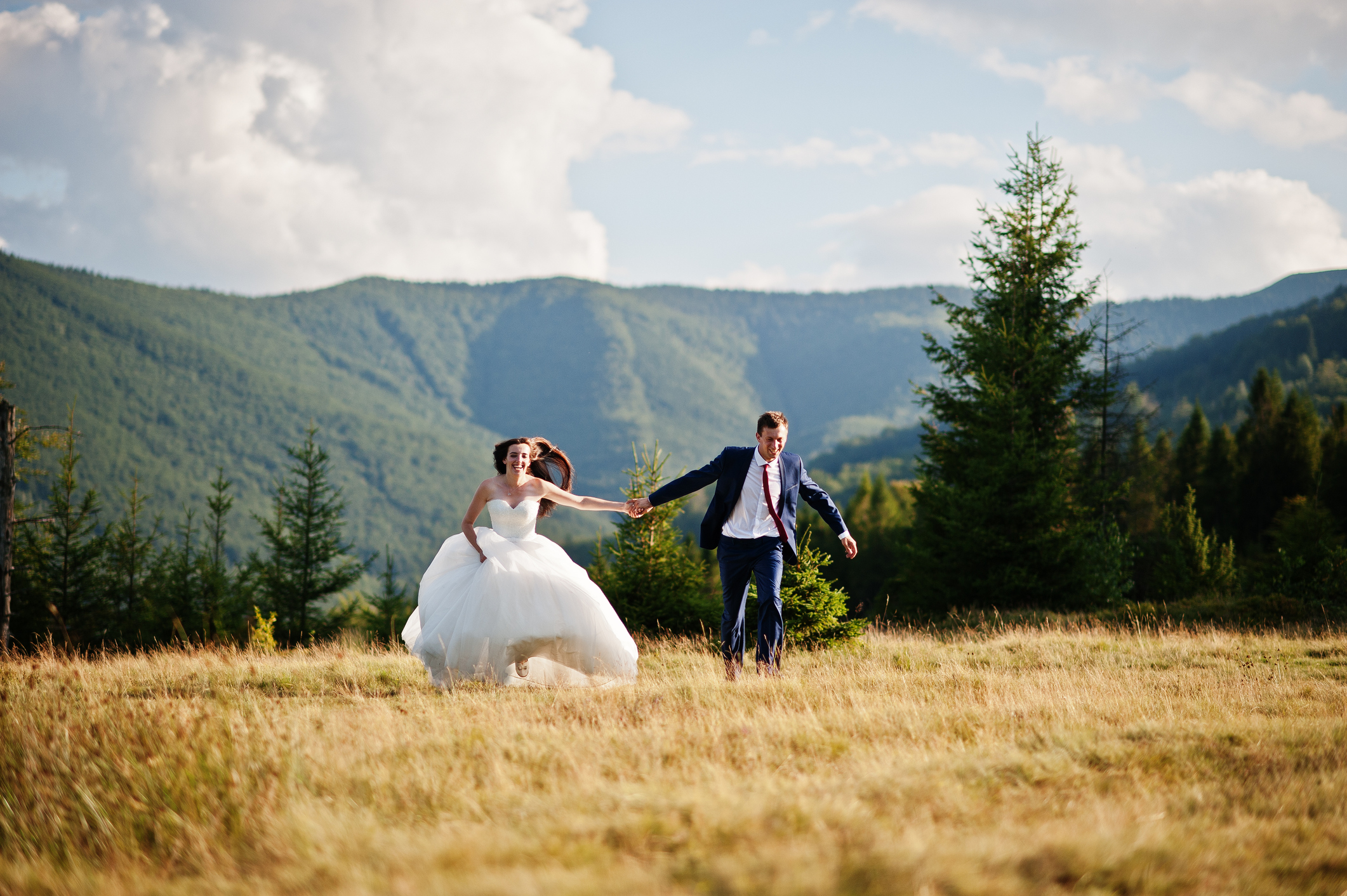 Lovely wedding couple running at amazing landscapes of Carpathian mountains.