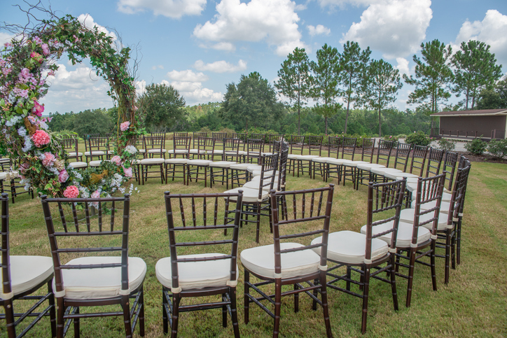 Unique round spiral chair pattern wedding ceremony setting at rolling hills countryside with brown Chiavari chairs and white cushions